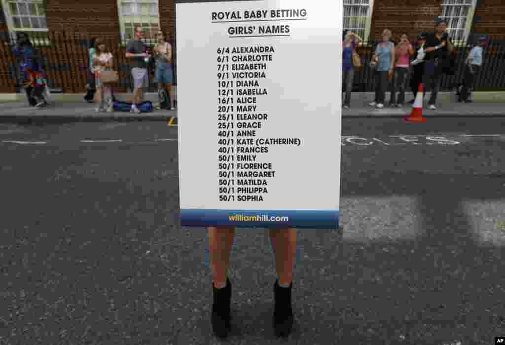 A bookmaker agency employee poses for the photographers with a board of odds regarding the royal baby's name near St. Mary's Hospital, London, July 17, 2013.