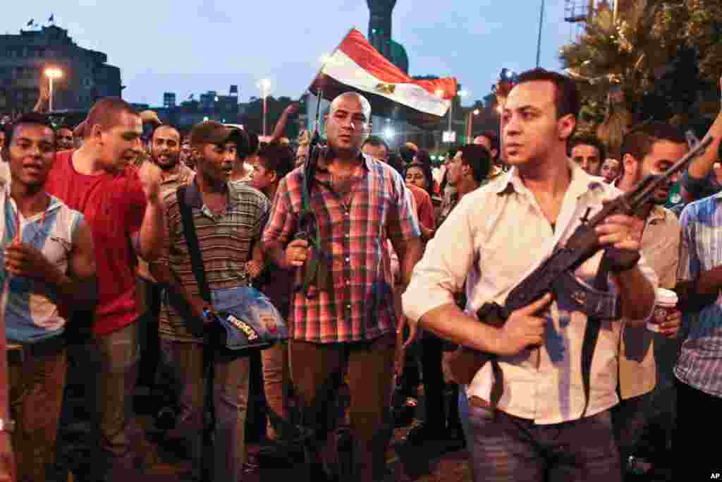 Polisi berpakaian preman berjalan bersama demonstran penentang Presiden Mesir Mohammed Morsi di tempat bentrokan dengan demonstran pendukung Morsi di Giza, Mesir (2/7). (AP/Roger Anis, koran El Shorouk)