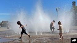 Anak-anak menyejukkan diri dengan bermain di air mancur di pusat kota Portland, Oregon, Jumat, 12 Mei 2023. (AP/Claire Rush)