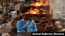 Des proches d'un homme décédé à cause du coronavirus pleurent avant sa crémation dans le village de Giddenahalli, dans la banlieue de Bengaluru, en Inde, le 13 mai 2021.