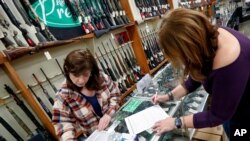 Andrea Schry, right, fills out the buyer part of legal forms to buy a handgun as shop worker Missy Morosky fills out the vendors parts after Dukes Sport Shop reopened, March 25, 2020, in New Castle, Pa. under the new conditions specified for gun stores.