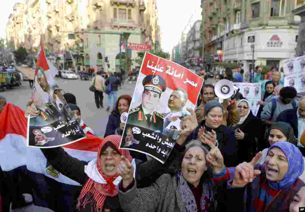 Activists shout anti-terrorism slogans as they hold posters with Arabic slogans that read, "Egypt is entrusted to us. The army and people are one hand," during a rally in Cairo, Dec. 26, 2013.