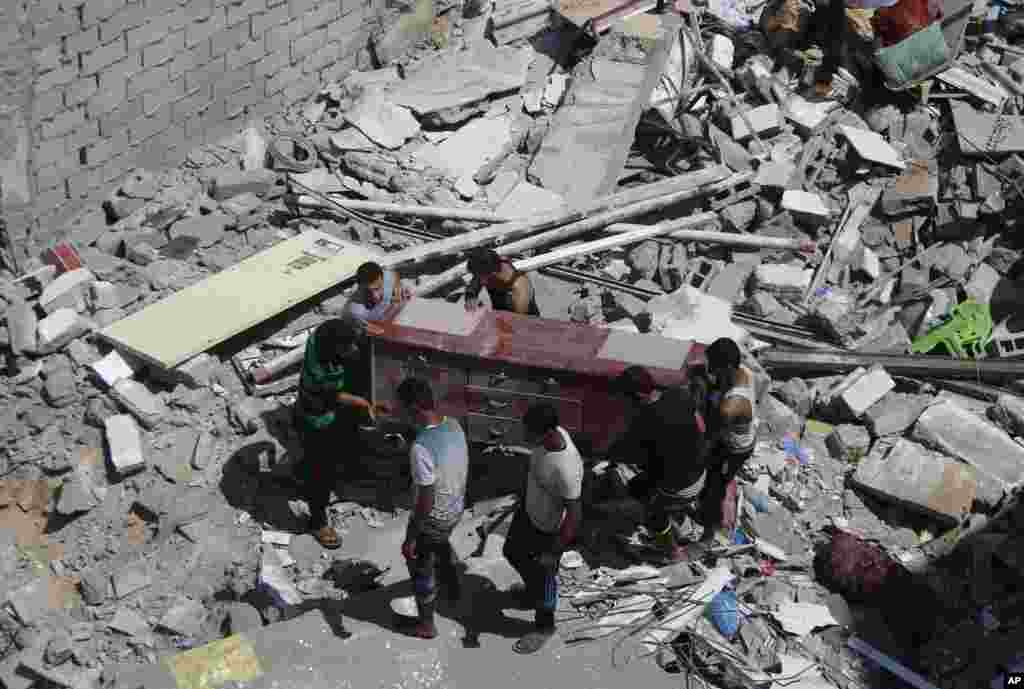 Members of the Issal family salvage belongings from their house that was destroyed in an overnight Israeli strike in Gaza City, Aug. 2, 2014.