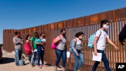 A group of Brazilian migrants walk around a gap in the U.S.-Mexico border in Yuma, Ariz., seeking asylum in the United States after crossing over from Mexico, June 8, 2021.