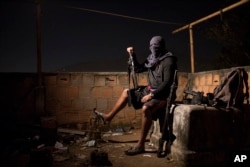 A drug gang leader poses for a photo, July 6, 2016, in a slum in Rio de Janeiro, Brazil. He told the Associated Press that drug dealers win the hearts and minds of locals by paying for food and medicine.