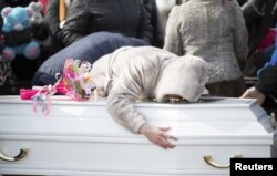A woman reacts during a funeral of a victim of a shopping mall fire at a cemetery in Kemerovo, Russia March 28, 2018.