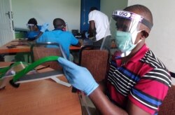 Pekerja menyiapkan pelindung wajah dari plastik daur ulang di bengkel Zaidi Recyclers sebagai langkah untuk menghentikan penyebaran COVID-19 di Dar es Salaam, Tanzania, 27 Mei 2020. (Foto: AFP)