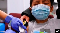 Julian Salgado, 7, menerima dosis kedua vaksin Pfizer COVID-19 di Gereja Komunitas Northwest di Chicago, Sabtu, 11 Desember 2021. (Foto: AP)