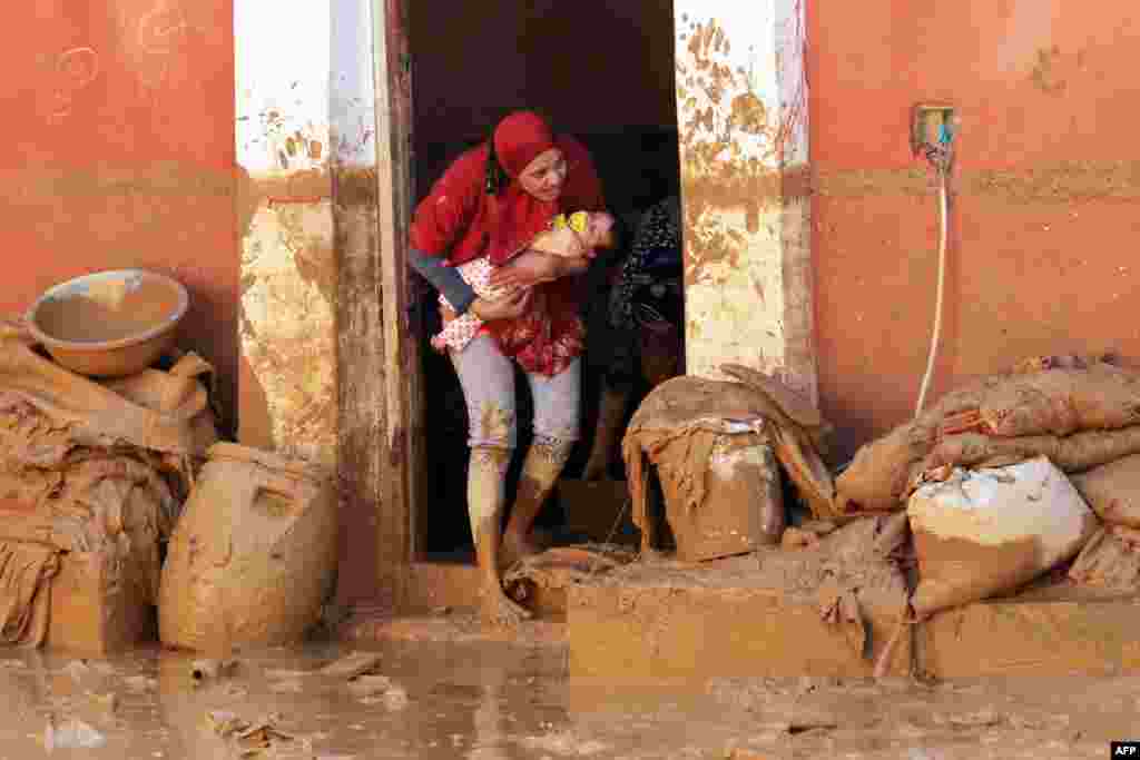 Seorang perempuan Mesirmenggendong bayinya di Ras Gharib, dekat Teluk Suez setelah banjir dan hujan melanda sebagian kawasan di sana.