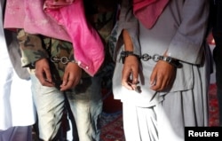 Two men in handcuffs, whom the police said belong to the Tehreek-e-Taliban Pakistan [TTP] group, are shown during a news conference at the Crime Investigation Department after their arrest, in Karachi, January 2013.