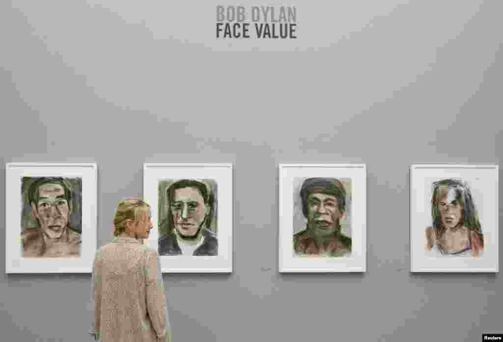 Seorang asisten galeri mengamati lukisan-lukisan pastel pada Pameran "Bob Dylan: Face Value" di National Portrait Gallery di London. Lukisan-lukisan pastel baru dari penyanyi Amerika Bob Dylan akan dipamerkan untuk pertama kalinya di National Portrait Gallery London dari 24 Agustus hingga 5 Januari.
