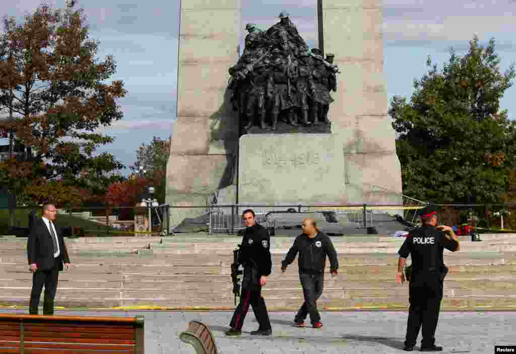 Police officers patrol the scene near the Canada War Memorial following a shooting incident in Ottawa.