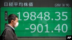 Un homme passe devant un panneau d'affichage électronique montrant l'indice japonais du Nikkei 225 à Tokyo, le lundi 9 mars 2020. (Photo: AP/Eugene Hoshiko)