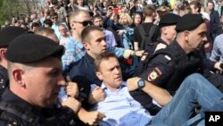 Polisi Rusia membopong kelompok oposisi Alexei Navalny (tengah), dalam sebuah unjuk rasa memprotes pelantikan Presiden Vladimir Putin di Alun-alun Pushkin di Moskow, 5 Mei 2018. 