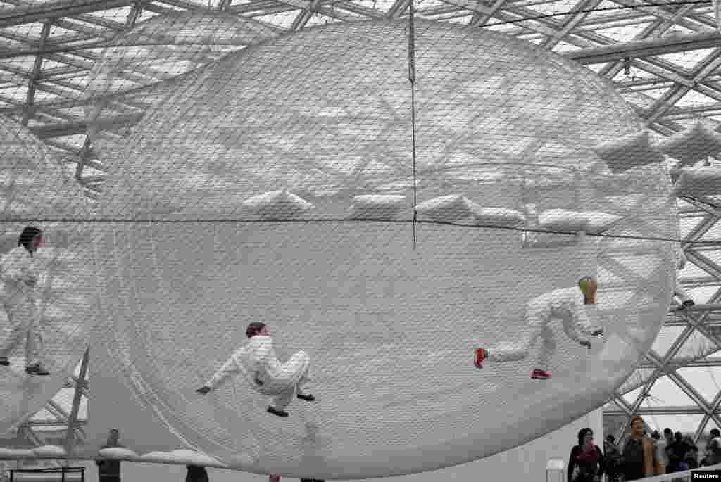 Visitors climb through the art installation 'In Orbit' by Tomas Saraceno of Argentina at the Kunstsammlung K21 museum in Düsseldorf, Germany, June 30, 2013. The steel wire construction spans the museum's vast glass cupola on three different levels more than 25 meters above the ground. Visitors have access to the artwork and can move freely between the spheres on all three levels.