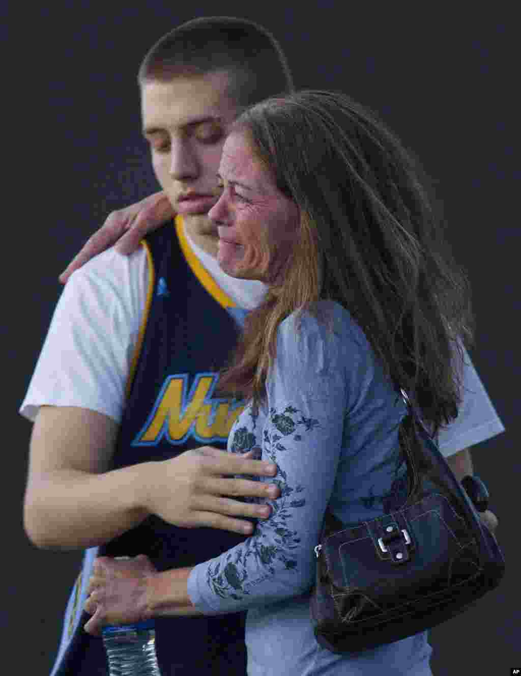 Jacob Stevens, 18, hugs his mother Tammi Stevens after being interviewed by police outside Gateway High School where witnesses were brought for questioning after a shooting at a movie theater, in Denver, Colorado, July 20, 2012.