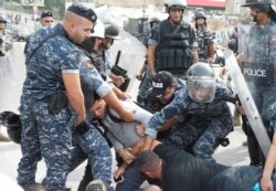 Police carry a demonstrator during an operation to open a blocked highway during ongoing anti-government protests in Beirut, Lebanon, Oct. 26, 2019.