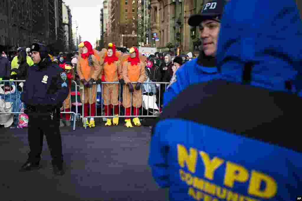 Spectators dressed as turkeys stand behind police barricades as they wait for the 87th Annual Macy's Thanksgiving Day Parade, New York, Nov. 28, 2013.