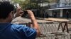 FILE - A journalist and a police officer take pictures of each other as people protest against the military coup in Yangon, Myanmar, February 23, 2021.