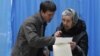 A young man helps an elderly voter read her voting ballot at a polling station in Kiev, Ukraine, Sunday, Oct. 28, 2012.