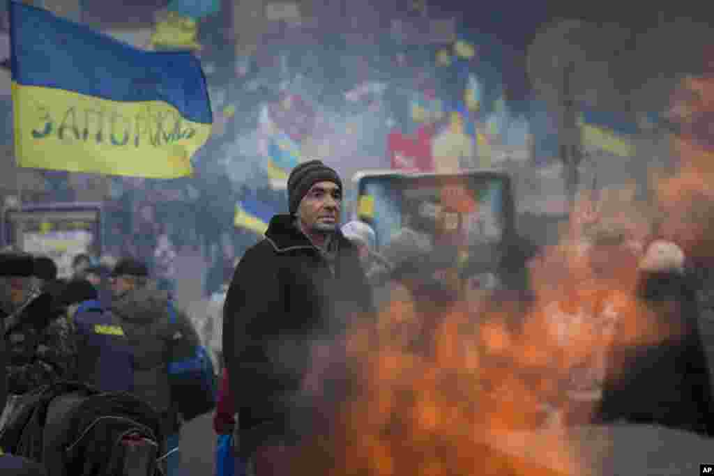 A pro-European Union activist stands while warming himself near a bonfire at a heavily fortified tent camp in Independence Square in Kyiv, Dec. 17, 2013.