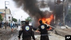 Foto dari Azaz Media Office, kelompok anti pemerintah Suriah, menunjukkan anggota Helm Putih yang memadamkan mobil yang terbakar.