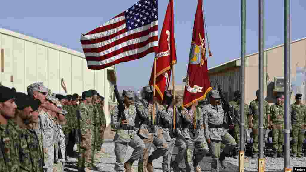 U.S. Marines march with flags during a handover ceremony, as the last U.S. Marines unit and British combat troops end their Afghan operations, in Helmand province, Oct. 26, 2014.