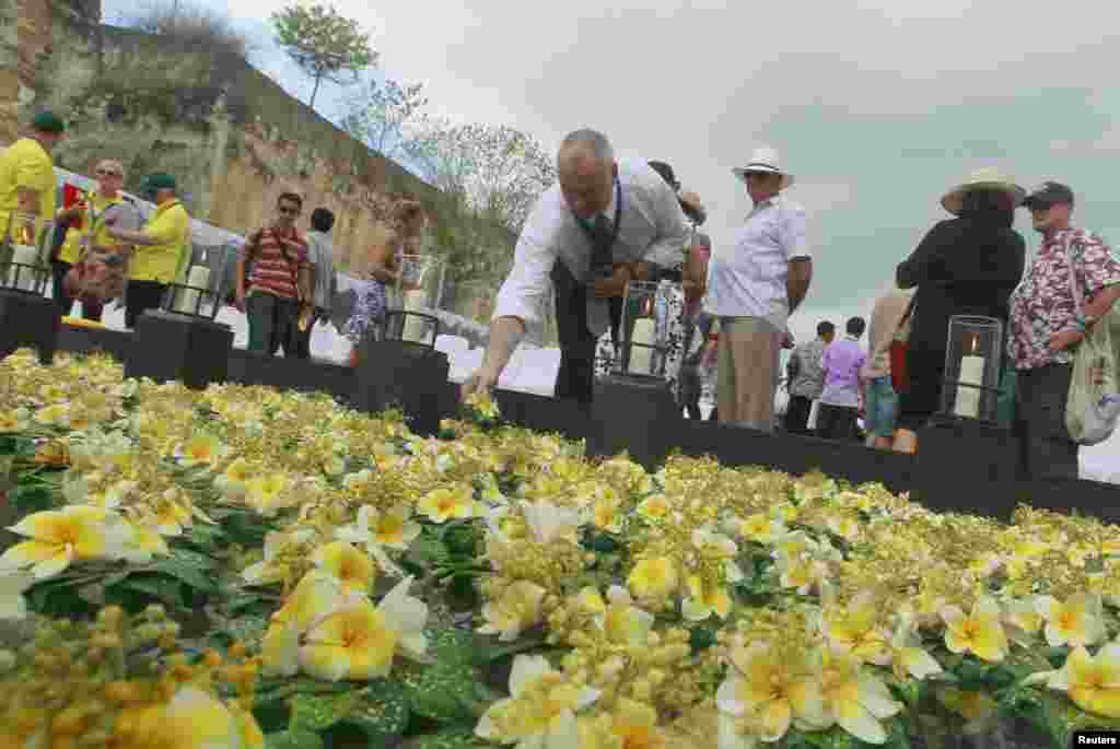 A man lays a flower on a pond for victims of the 2002 Bali bomb attack during the commemoration service for the 10th anniversary of the Bali bombing, Jimbaran, Bali, October 12, 2012.