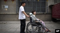 Di foto yang diambil tanggal 30 Juni 2010 ini, Ni Yulan (duduk di kursi roda) dibantu Don Jiqin, suaminya, menikmati udara sore Beijing (Foto: dok). Mahkamah banding Tiongkok membatalkan vonis penipuan atas pengacara aktivis difabel Ni Yulan yang dipenja