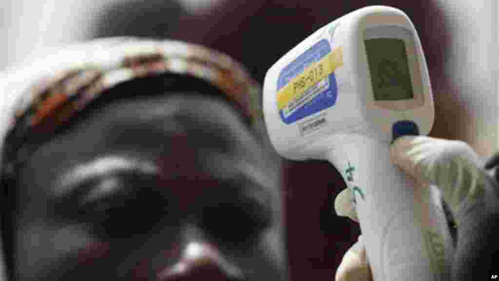 Wani jami’in kula da lafiyar matafiya na amfani da ma’aunin zafin jiki ya na yiwa Maniyyata gwajin cutar Ebola a ranar goma sha takwas ga watan satumba shekarar dubu biyu da goma sha hudu, 18 ga Satumba, 2014.