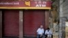 A security guard, right, reads a newspaper as he sits in front of a closed ATM in New Delhi, India, April 18, 2018. Several ATMs were seen to have run dry across the country, reportedly from a surge in demand of cash withdrawals. 