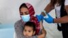 FILE - A migrant holds her baby as she receives a shot of the Johnson & Johnson vaccine against the coronavirus disease (COVID-19) in the Mavrovouni camp for refugees and migrants on the island of Lesbos, Greece, June 3, 2021.