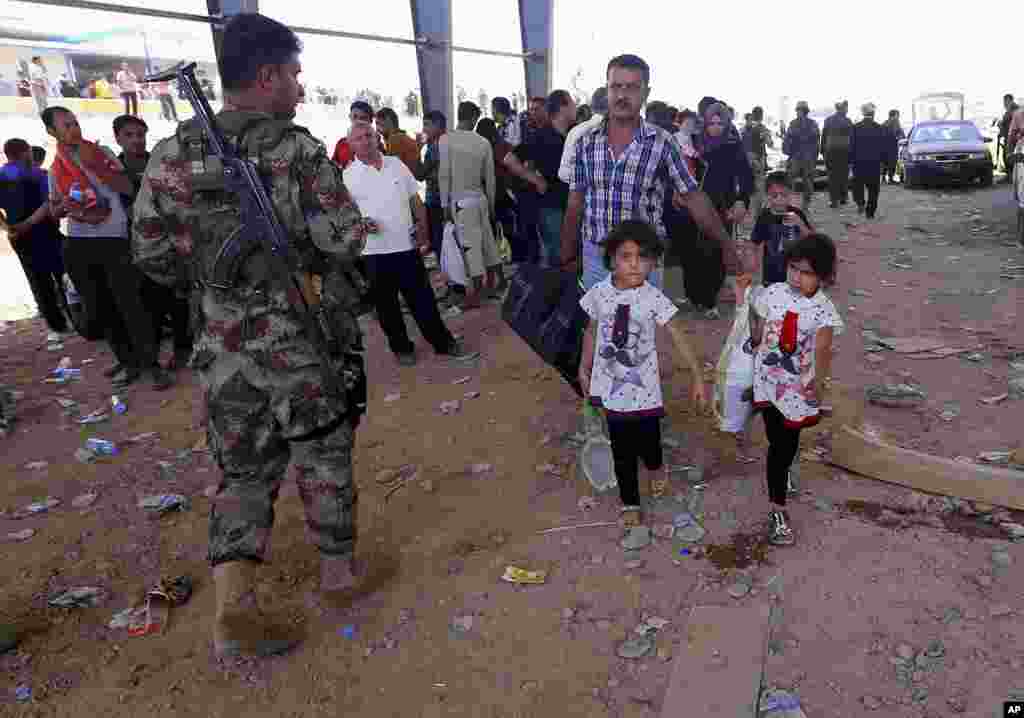 Polisi Kurdi berjaga-jaga sementara para pengungsi dari Mosul mengarah ke wilayah otonom Kurdi di Irbil, Irak, 350 kilometer dari Baghdad (10/6). 