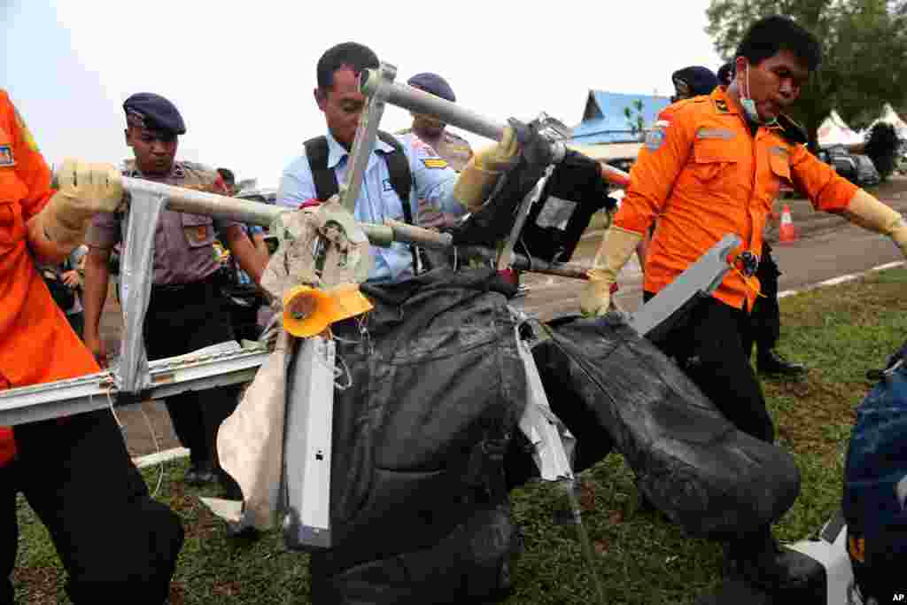 Anggota Badan SAR Nasional (Basarnas) mengangkat tempat-tempat duduk pesawat AirAsia bernomor penerbangan 8501 setelah diangkut oleh helikopter Angkatan Udara AS di bandar udara Pangkalan Bun (5/12). (AP/Tatan Syuflana)