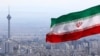 FILE - Iran's national flag flutters in the wind as the Milad telecommunications tower and buildings are seen in the background, in Tehran, Iran, March 31, 2020. 