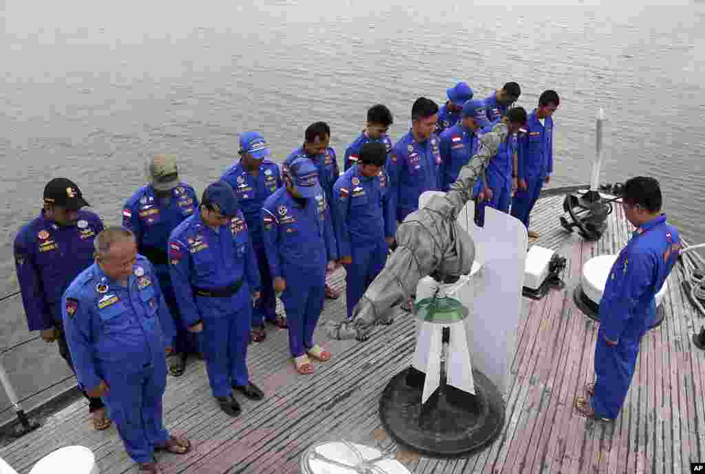 Anggota Polisi Penjaga Pantai Indonesia berdoa di atas kapal pencari dalam operasi pencarian pesawat AirAsia QZ8501 yang hilang, di pelabuhan Pangkal Pinang di pulau Sumatra, Indonesia, 29 Desember 2014.