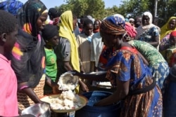 FILE - Cameroonians who fled deadly intercommunal violence between Arab Choa herders and Mousgoum and Massa farming communities receive food at a temporarily refugee camp on the outskirts of Ndjamena, Chad, Dec. 13, 2021.