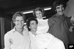 FILE - Actor Harrison Ford, left, who played Han Solo in the move "Star Wars," is pictured with his co-stars, Anthony Daniels, who played C-3P0; Carrie Fisher, who played Princess Leia; and Peter Mayhew, who played Chewbacca, as they take a break from filming a television special, Oct. 5, 1978.