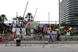 A man walks past a memorial site created by neighbors as search and rescue efforts resume the day after the managed demolition of the remaining part of Champlain Towers South complex in Surfside, Florida, July 5, 2021.