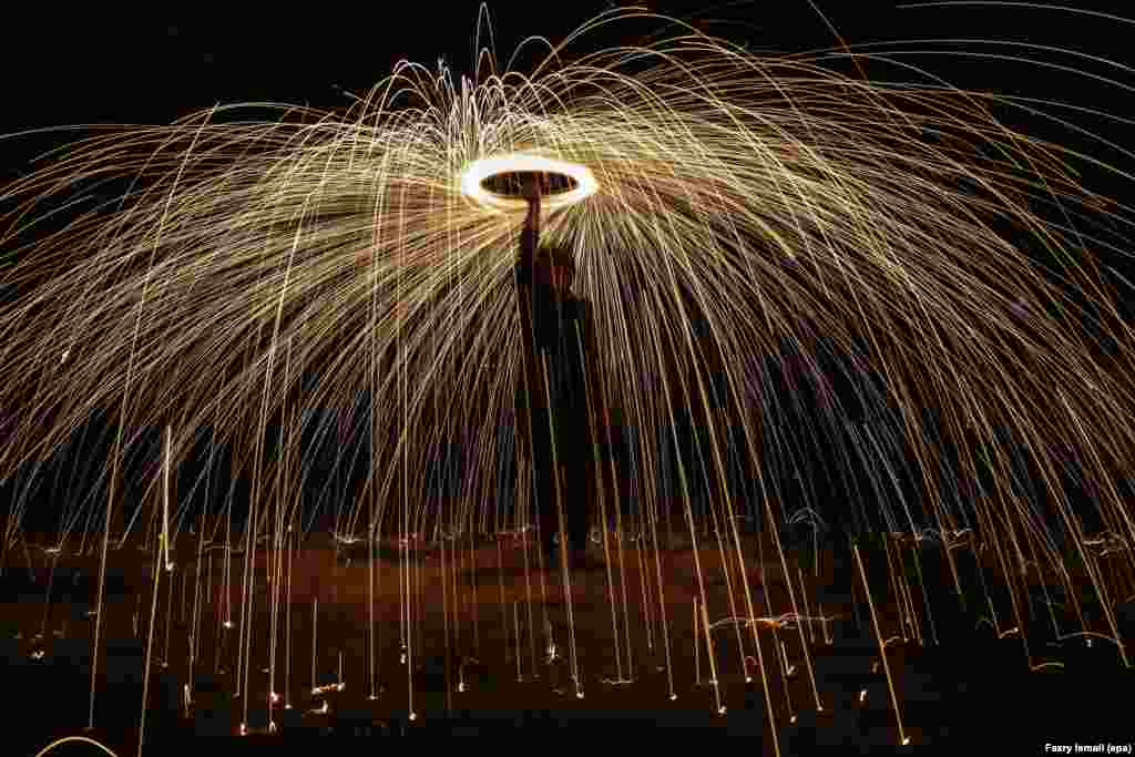 A Malaysian swings around fireworks to celebrate the last day of the Muslims' Holy fasting month of Ramadan, in Shah Alam, outside Kuala Lumpur, Malaysia, July 04, 2016.