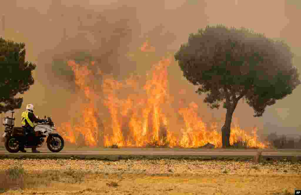 Nan ma wani dan sanda ne yake kallon wutar daji yayin da yake kan babur dinsa a kudancin Spain, ranar 25 ga watan Yuni (AP Photo/Alberto Diaz)