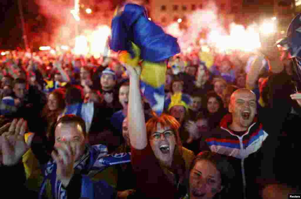 Para penggemar Bosnia dan Herzegovina merayakan gol melawan Argentina dalam pertandingan yang disiarkan langsung di alun-alun utama Sarajevo (16/5). (Reuters/Dado Ruvic)