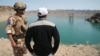 FILE - A British soldier stands with an Afghan interpreter with part of the Kajaki power dam in the background in Kajaki, Helmand province, south of Kabul, Afghanistan, April 16, 2008.