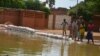 Quelques personnes dans une rue inondée par le fleuve Niger dans le quartier Saga de Niamey le 11 septembre 2017.