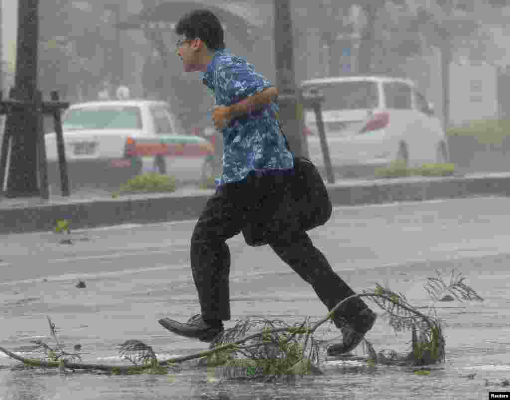 A man walks across a road at a pedestrian crossing amidst strong winds caused by Typhoon Neoguri in Naha, on Japan's southern island of Okinawa, in this photo taken by Kyodo, July 8, 2014. 