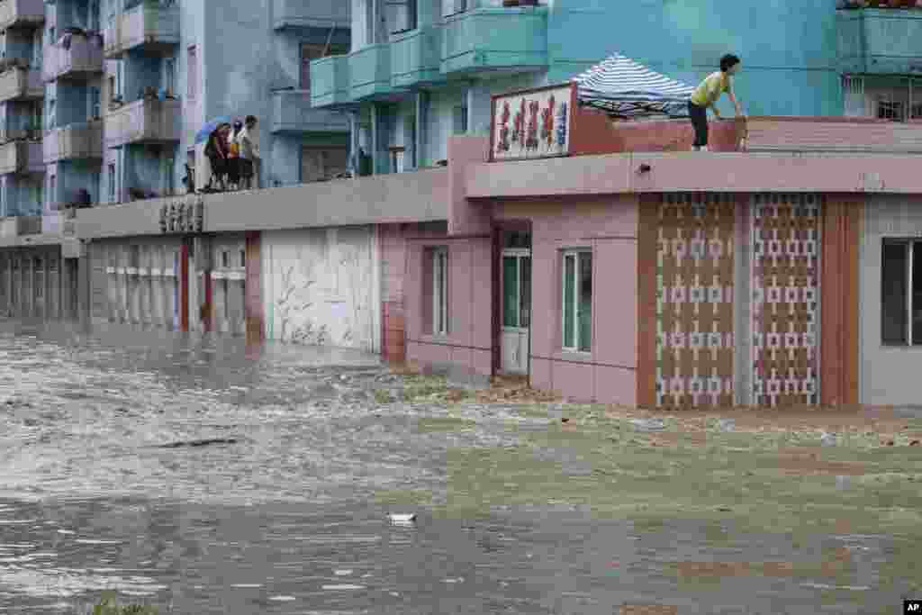 Residents wait on the roof of a flooded building in Anju City, South Phyongan Province, North Korea, July 30, 2012.