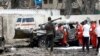 Seorang petugas polisi berjaga-jaga saat pekerja Bulan Sabit Merah mengeluarkan jenazah korban di lokasi ledakan bom mobil bunuh diri di dekat kediaman presiden, di Mogadishu, Somalia, 25 September 2021. (Foto: Reuters)