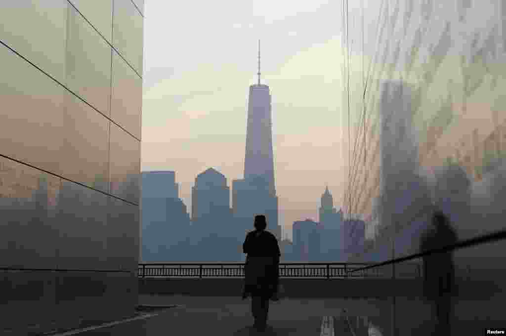 A woman looks out at New York's Lower Manhattan and One World Trade Center from inside the Empty Sky memorial at Liberty State Park in Jersey City, New Jersey, Sept. 11, 2013.
