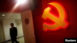 A man walks past a Communist Party logo as he attends a training course at a Communist Party's China Executive Leadership Academy, in Shanghai, Sept. 24, 2012. Party delegates now face new anti-corruption rules when using the WeChat social media platform.