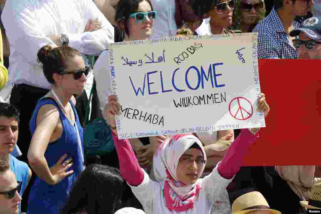 A woman holds up a sign as she watches U.S. President Barack Obama at the Brandenburg Gate in Berlin, June 19, 2013.